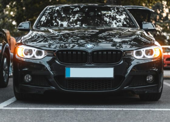 Black BMW sedan parked under trees