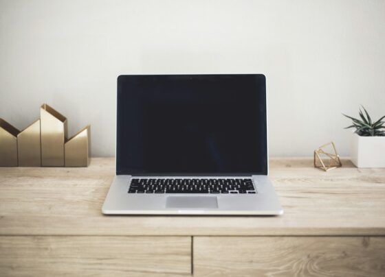 Open laptop with a dark screen on a wooden desk.