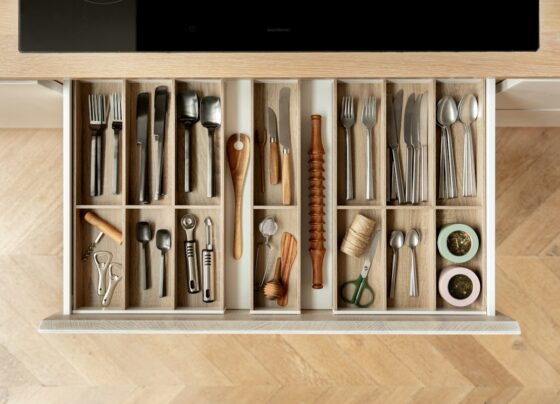 Open kitchen drawer with wooden compartments separating cutlery and cooking utensils.