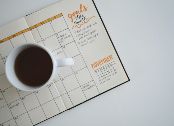 Open paper calendar and planning notebook with a cup of coffee.