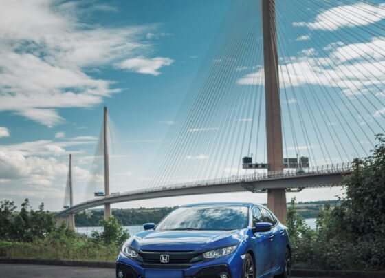 Blue Honda car beside a bridge