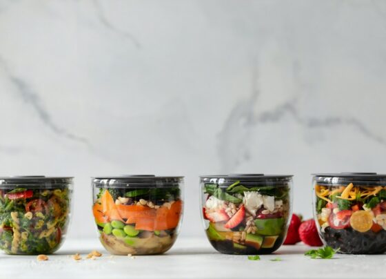Four lidded clear food containers filled with colorful prepared vegetables.