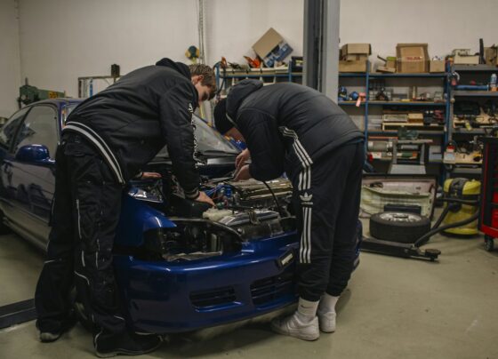 Two mechanics working in an open car engine bay