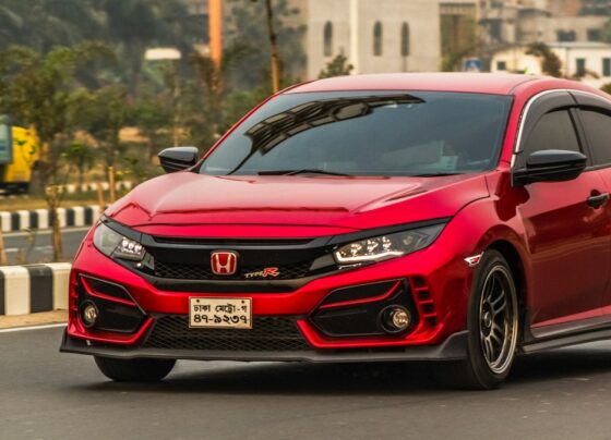 Red Honda hatchback parked beside a road