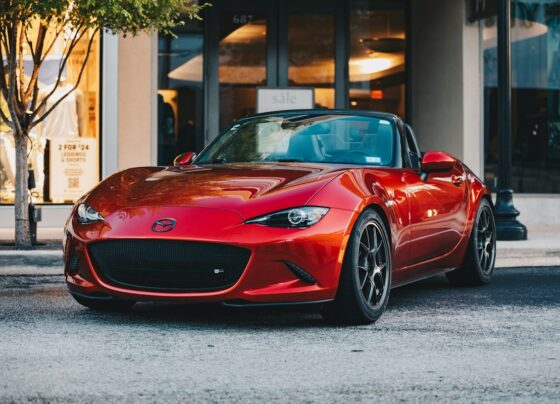 Red Mazda sports car parked beside a building