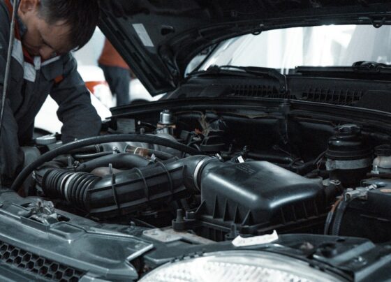 Mechanic inspecting an open car engine bay