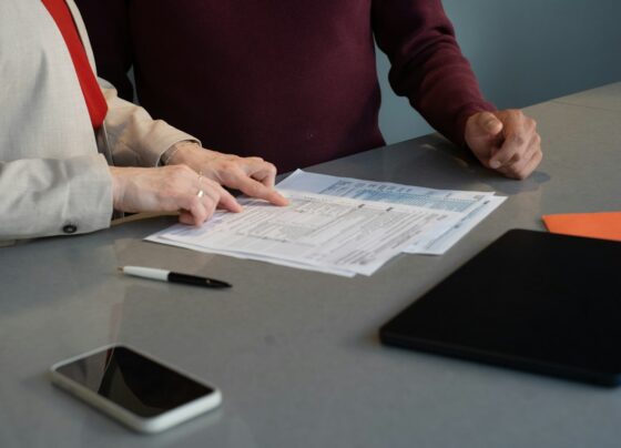 Two people reviewing printed paperwork at a table.