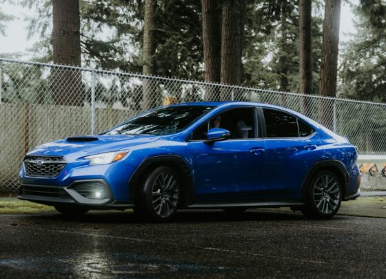 Blue Subaru sedan parked beside a fence