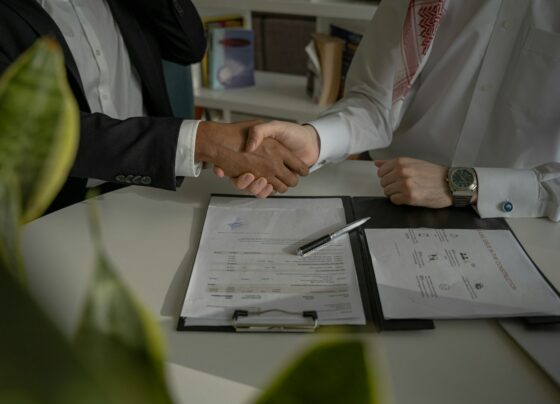 Two people shaking hands over paperwork